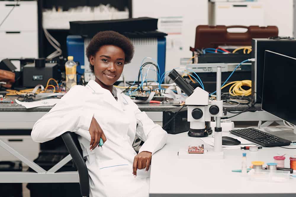 A Black female scientist smiles confidently in a lab