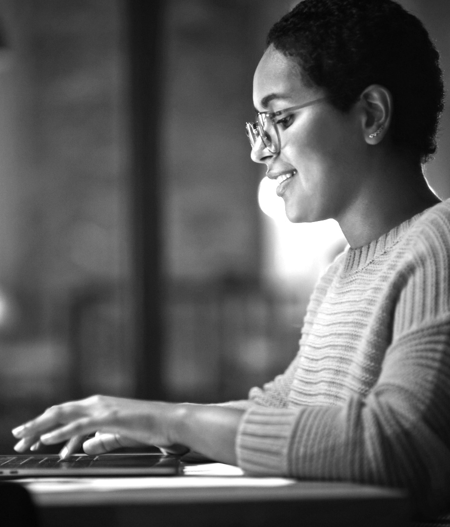 A young black woman smiles as she works on a computer