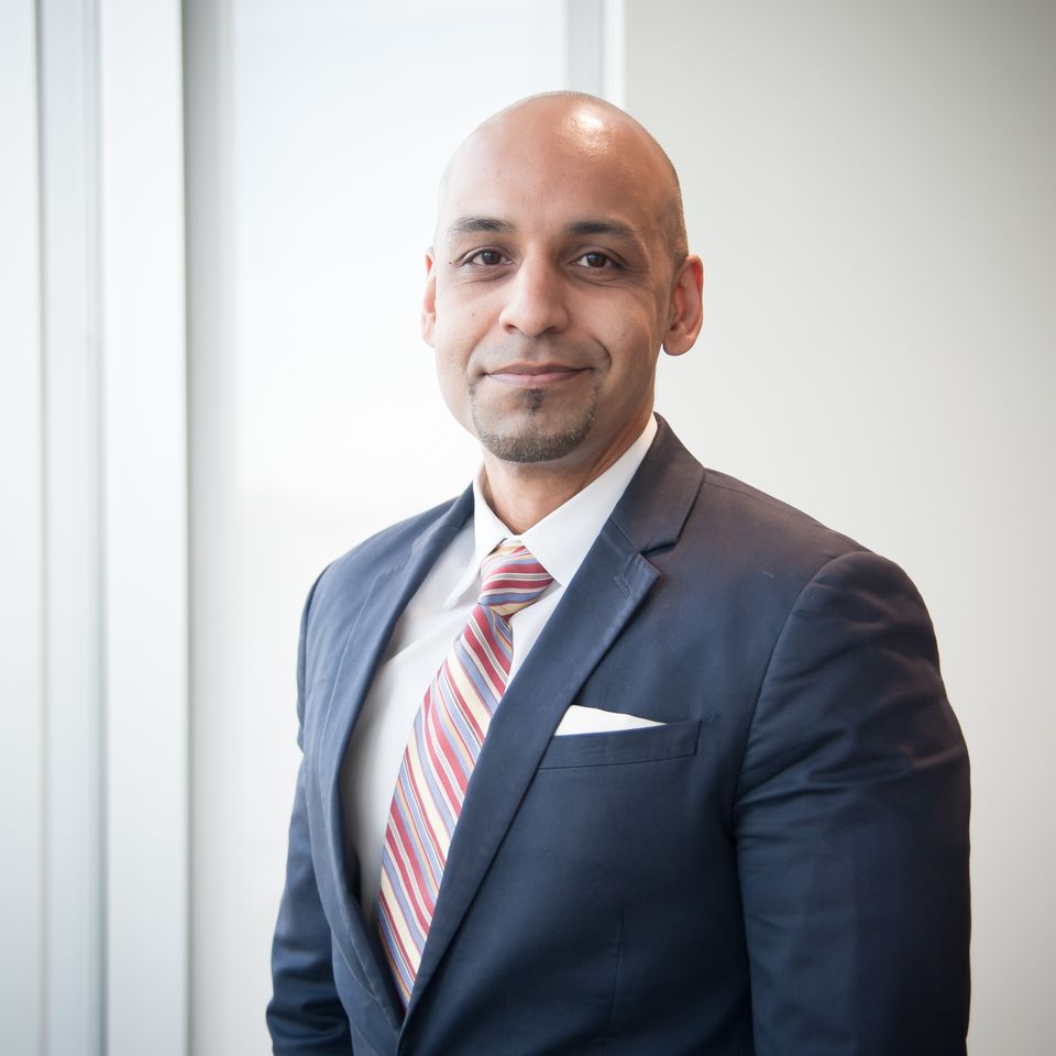 Hamid Bhatti, an I-Corps mentor, smiles in a suit and tie