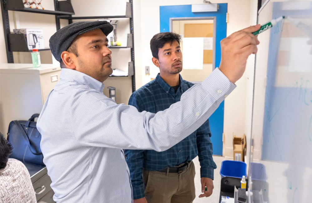 Doctoral student Shikhar Prakash, right, and Madhur Srivastava, assistant research professor in chemistry and chemical biology, work at a white board in the Physical Sciences Building.
