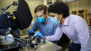 two people look with masks look at through a microscope